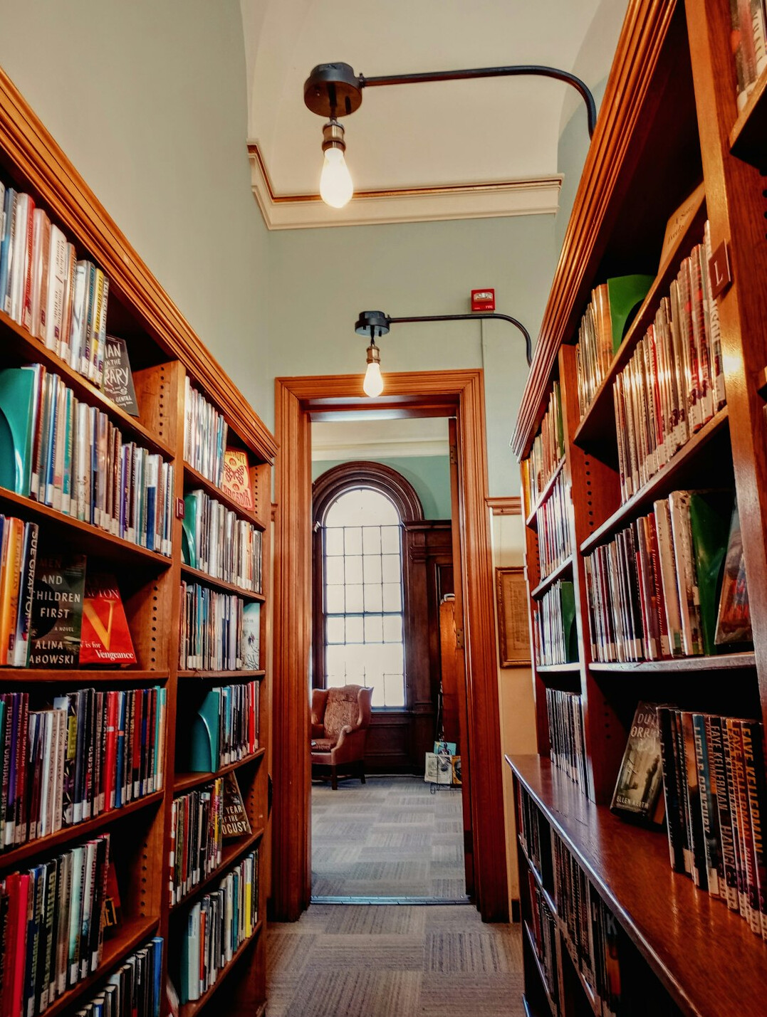 Old library with tall wooden bookshelves and warm lamps